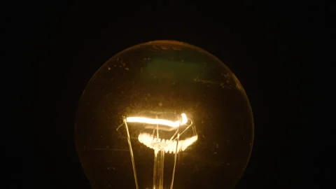Tungsten light bulb light turns on and off cozy on black background Stock Footage 236822475