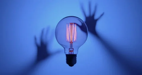 Tungsten light bulb with zombie hand on blue background Stock Footage 170167869
