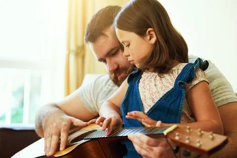 Tuning into a developing talent. an adorable little girl playing the guitar with Stock Photos