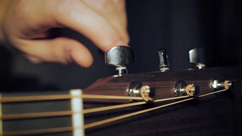 Tuning a Guitar. Male Hand Twisting the Tuner Knobs on a Beautiful Western Stock Footage
