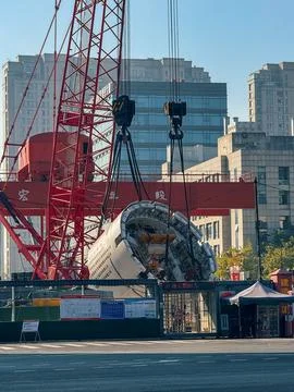 Tunnel boring machine section lifted by massive red crane Stock-Fotos