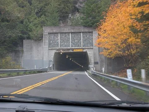Tunnel through a rugged mountain surrounded by autumn trees Stock Photos