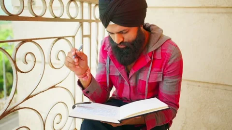 Turbaned male notes thought inside sketchbook on balcony Stock Footage 307900092