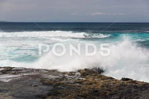 Turbulent ocean waves with white foam beat coastal stones Stock Photos
