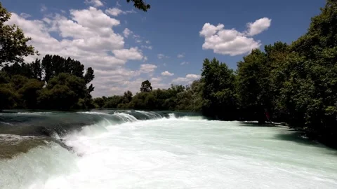 Turbulent River Rapids Cascading Through Lush Green Foliage Under a Partly .. Stock Footage 301088226