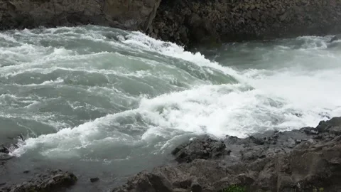 Turbulent river with strong currents and whitewater rapids flows through a rocky Stock Footage 346326218
