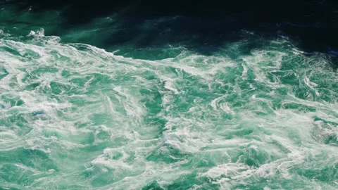 Turbulent river water flows rapidly, creating foamy white rapids and mesmer.. Видео 334718220