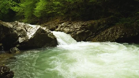A turbulent stream of water tumbles down a small rock ledge in the riverbed Stock Footage 277873456