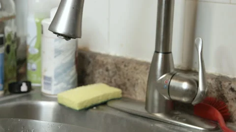 Turing on a kitchen faucet during the evening Video stock 63058551