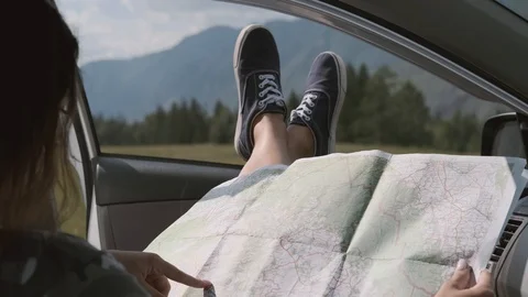 The Turisk girl looks at a map while sitting in a car and sticking his legs out Stock Footage 113809789