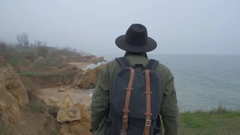 Turist with a backpack on a walk on the edge of a cliff Stock Footage 106776078