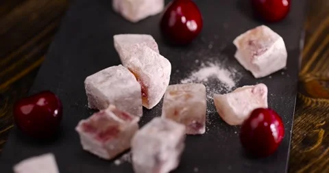 Turkish delight slices with cherry on a black slate board , cubes of sweet Stock Footage 305245359