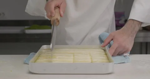 Turkish dessert baklava preparation using traditional recipe. Pastry chef cut Stock Footage 293846242