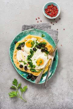 Turkish eggs flatbread with yoghurt, cheese, olives, spinach and red pepper o Stock Photos