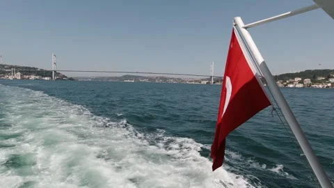 Turkish flag on ferry with Bosphorus bridge and foamy wake, clear day Stock Footage 320029531