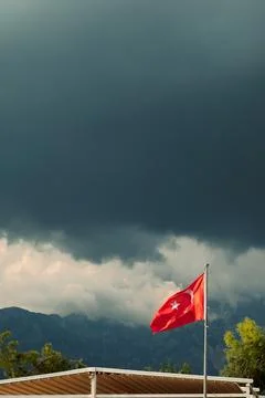 Turkish flag waves under dark clouds in a stormy sky near mountains in Turkey Fotos Stock