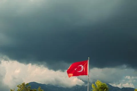 Turkish flag waves under dark clouds in a stormy sky near mountains in Turkey Fotos Stock