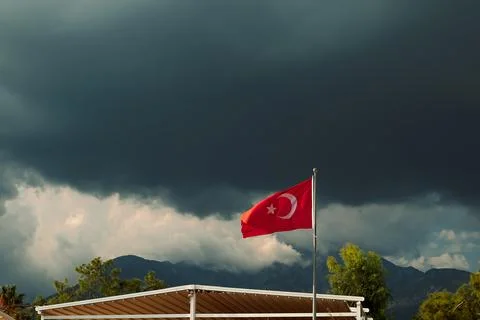 Turkish flag waves under dark clouds in a stormy sky near mountains in Turkey Stock Photos
