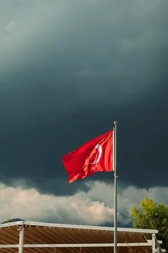 Turkish flag waves under dark clouds in a stormy sky near mountains in Turkey Stock Photos