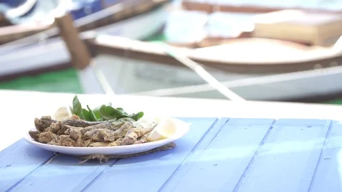 Turkish Hamsi Tava with lemon and arugula on blue table. Fried Anchovies. Stock Footage 80307645