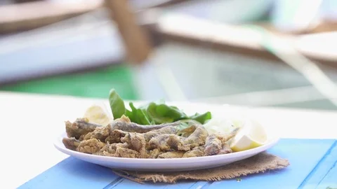 Turkish Hamsi Tava with lemon and arugula on blue table. Fried Anchovies. Stock Footage 80308671