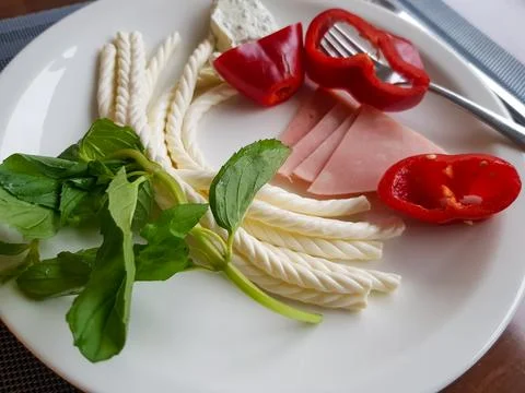 Turkish Helix String white Cheese with vegetables on plate with wooden back.. Foto stock