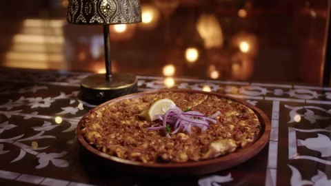 Turkish lahmacun dish with meat, lemon, and onion on a traditional table Stock Footage 345133934