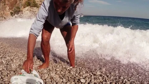Turkish man is cleaning fish in the foamy waves of the surf on the Mediterranean Stock Footage 81740475