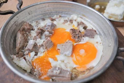Turkish scrambled eggs with roasted meat in copper pan Stock Photos