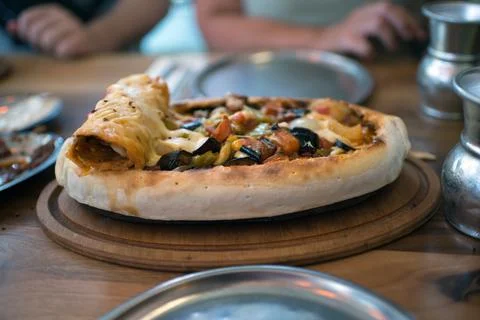 Turkish vegetable stew in flatbread. Incidental people at table Stock Photos