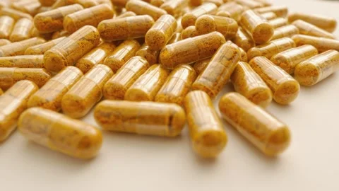 Turmeric capsules spin on a movable platform. Flying around the camera around Stock Footage 276312618