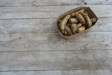 Turmeric roots in cardboard container on rustic wooden table 库存照片