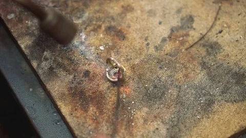 Turn and heating using a blowtorch silver ring on wooden table Video stock 73462608