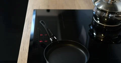 Turn on black induction or electrical cooktop surface with frying pan Stock Photos