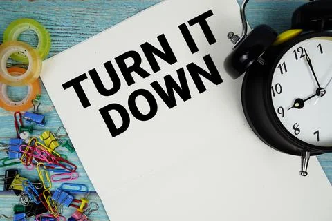 Turn It Down text with alarm clock and colorful office supplies on a blue w.. Stock Photos