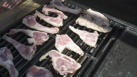Turn a lamb chop with a pair of kitchen tongs while cooking on a barbecue. Li Stock Footage 163651372