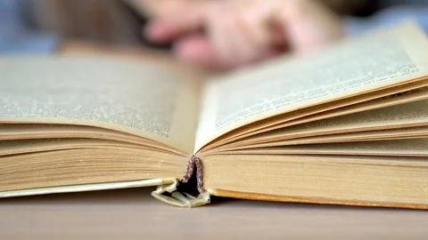 Turn over the sheet in the book lying on the table. Close up view. Stock Footage 125639284