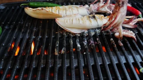 Turn over squids on the cast iron grill barbecue. Seafood. Slow motion Stock Footage 263317296