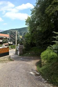 Turn in an uphill paved road in a forest bordered by the fence of a construct Stock Photos