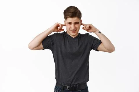 Turn volume off. Annoyed young man shut ears and grimace from terrible loud Stock Photos