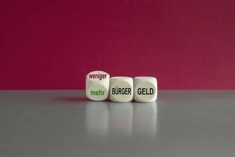 Turned a dice and changes the expression 'mehr Buergergeld' and 'weniger Buer Stock Photos