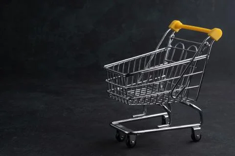 Turned pushcart empty on dark background, Black Friday concept. Stock Photos