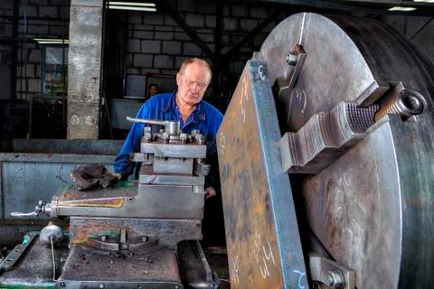 Turner machine operator controls processing of metal big turning lathe. Stock Photos