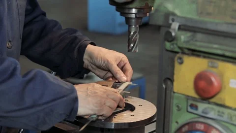 Turner is working on a lathe machine in a factory. Worker is measuring a produce Stock-Footage 111368372