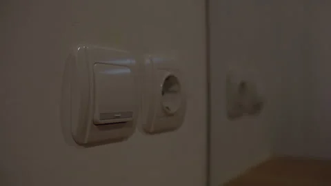 Turning a bedroom light switch on and off beside a wall power outlet Stock Footage 339197044