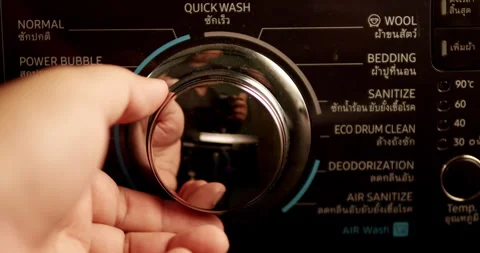 Turning the dial of a washing machine as the individual is preparing to Stock Footage 274530899