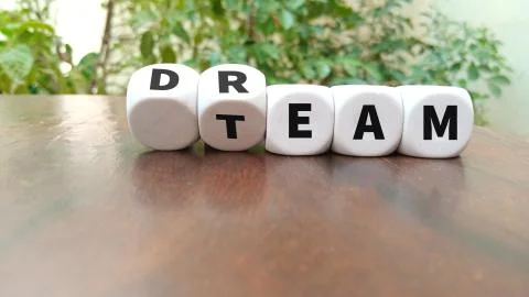 Turning a dice and changes the word dream to team Stock Photos