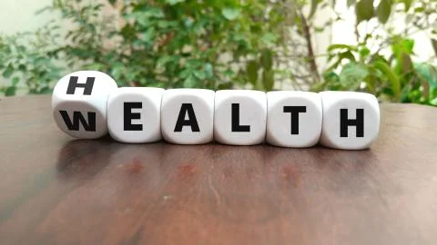 Turning a dice and changes the word Health to Wealth Stock Photos