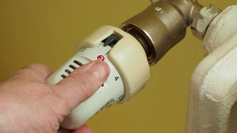 Turning down thermostat on radiator to save energy Stock Footage 212049272