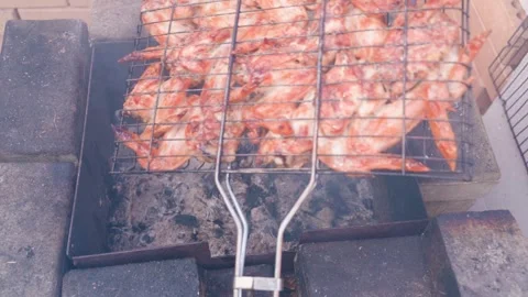Turning the grid with chicken wings over the grill Stock Footage 311796943